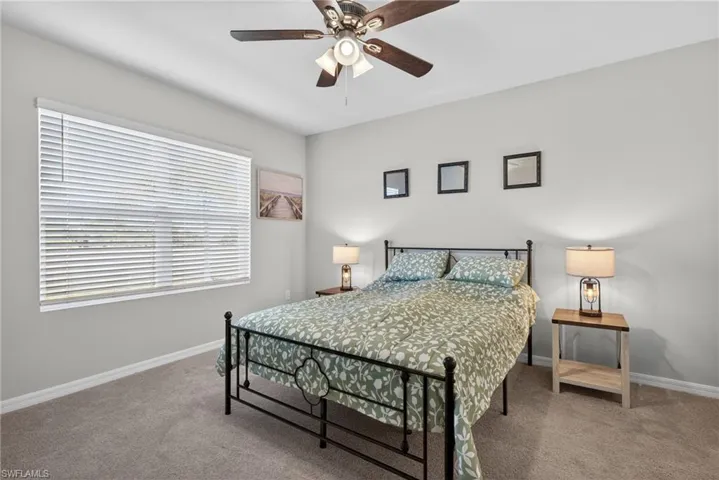 Carpeted bedroom featuring ceiling fan and baseboards