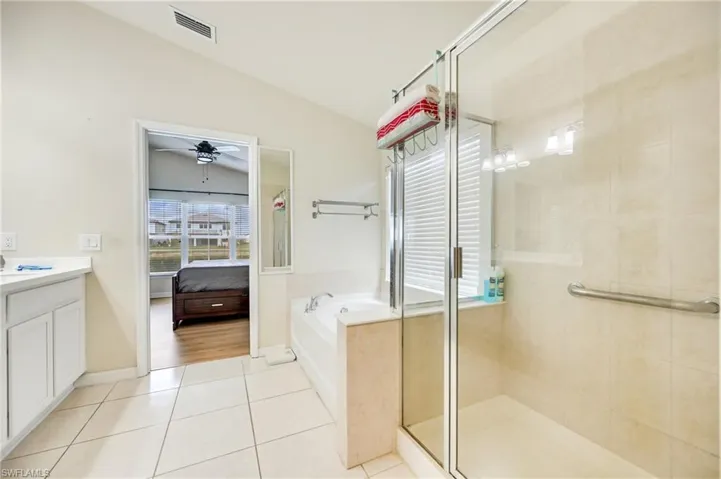 Full bath with vanity, ensuite bathroom, a garden tub, a shower stall, and vaulted ceiling
