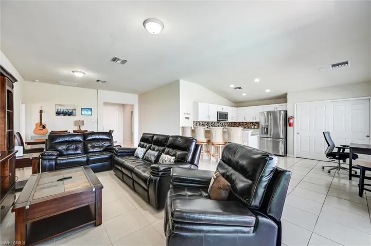 Living area with a desk, lofted ceiling, and light tile patterned floors