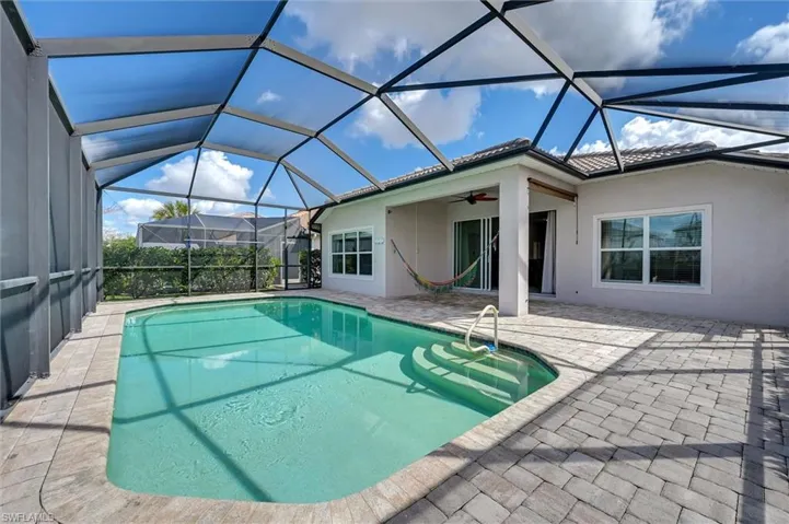 Swimming pool featuring a sunroom, a patio area, and a lanai