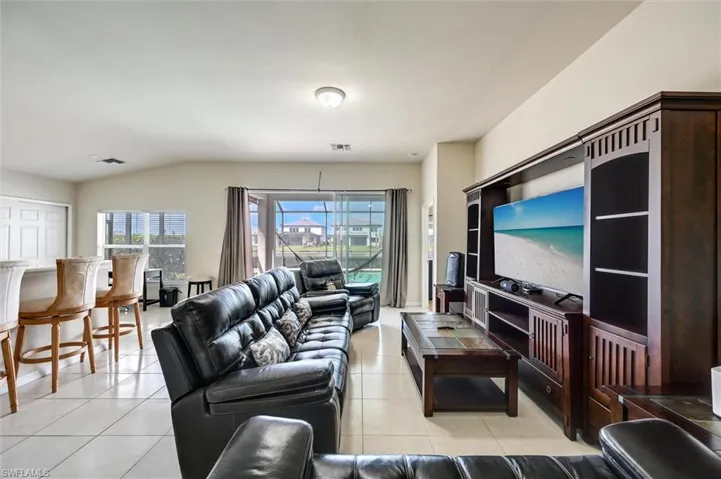 Living room with light tile patterned floors and vaulted ceiling