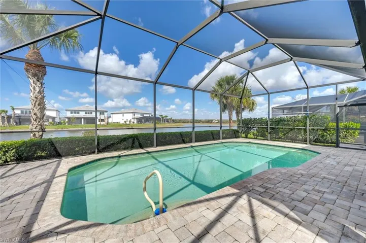 Swimming pool featuring a sunroom, a residential view, glass enclosure, a water view, and a patio area