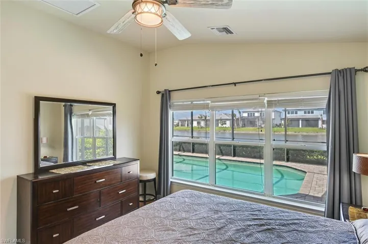 Bedroom with multiple windows, vaulted ceiling, ceiling fan, and a water view