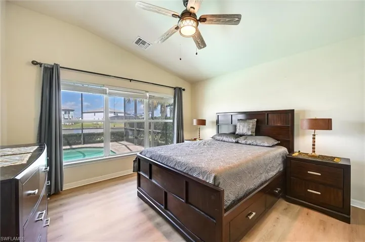 Bedroom featuring light wood-type flooring, lofted ceiling, and a ceiling fan