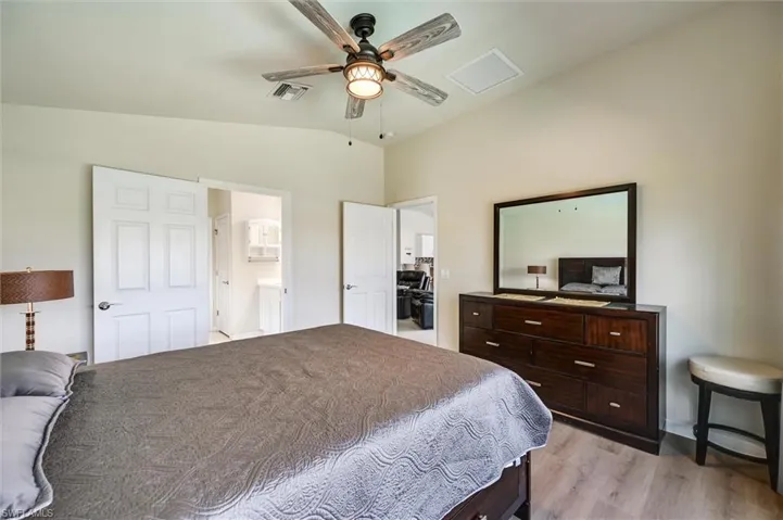 Bedroom with lofted ceiling, light wood finished floors, and ceiling fan