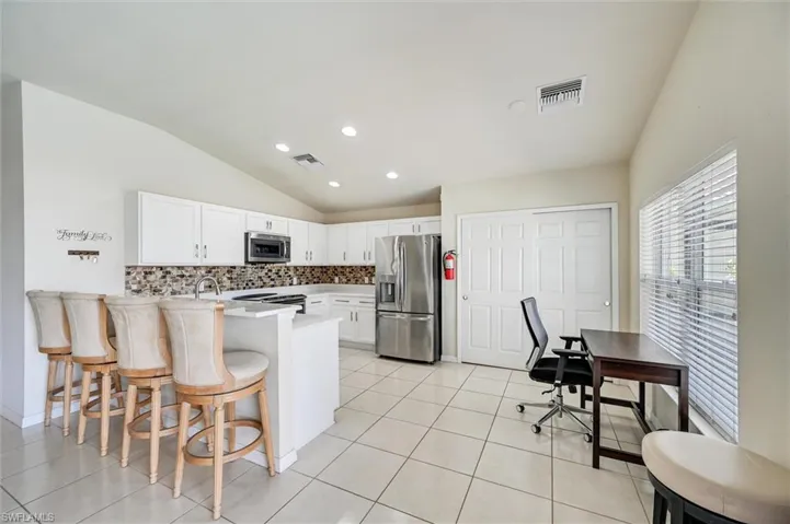 Kitchen with lofted ceiling, a breakfast bar area, stainless steel appliances, a peninsula, and white cabinetry