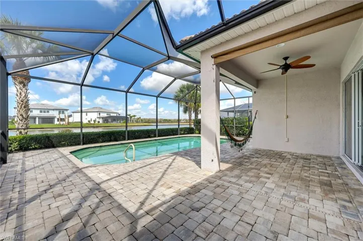 Swimming pool with a patio area, a sunroom, glass enclosure, and a residential view