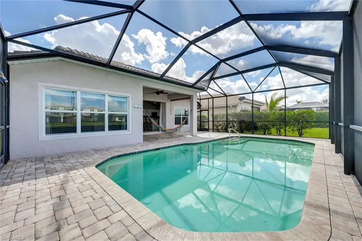 Outdoor pool with a sunroom, a patio, and glass enclosure