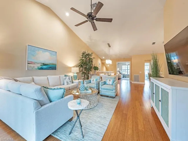 Living room with light hardwood / wood-style floors, high vaulted ceiling, and ceiling fan