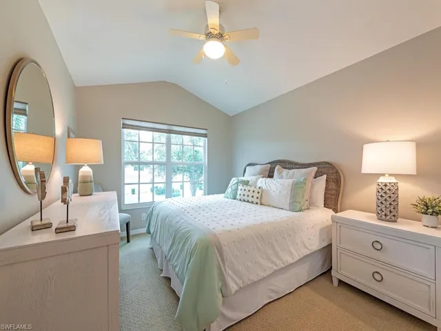 Carpeted bedroom with ceiling fan and lofted ceiling