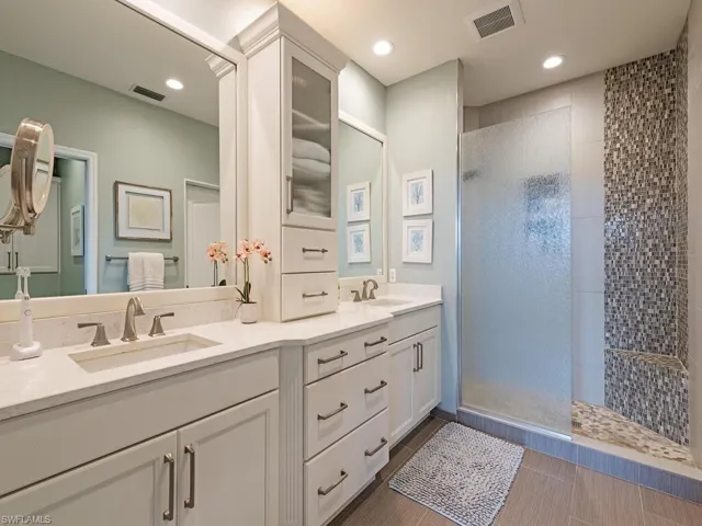 Bathroom featuring tile patterned floors, vanity, and tiled shower