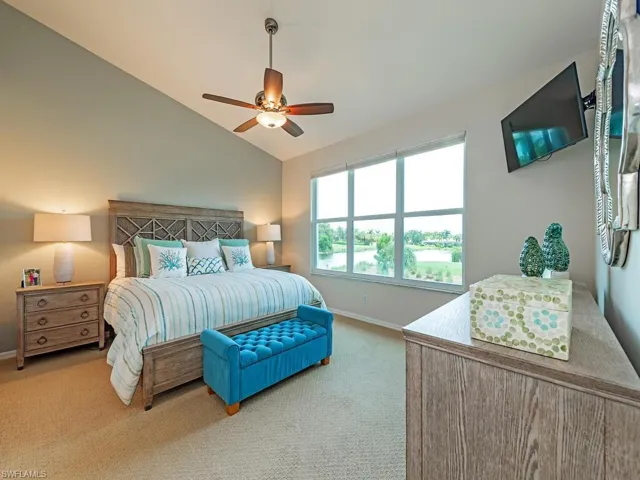Carpeted bedroom with ceiling fan and vaulted ceiling
