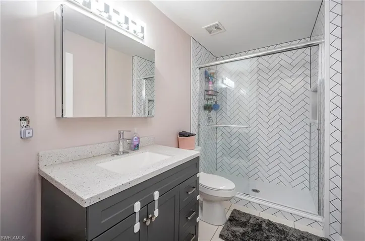 Bathroom with vanity, toilet, a shower with door, and tile patterned floors
