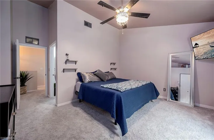 Carpeted bedroom featuring ceiling fan and high vaulted ceiling