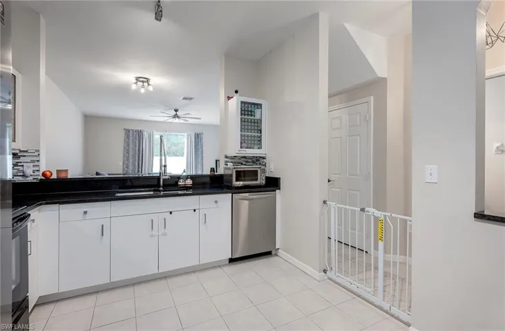 Kitchen with ceiling fan, white cabinets, sink, dishwasher, and decorative backsplash