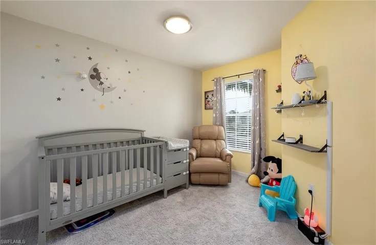 Carpeted bedroom featuring a nursery area