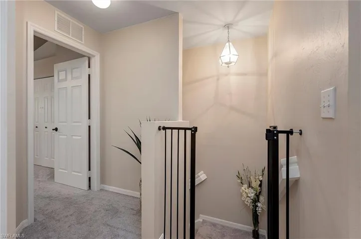 Corridor featuring light colored carpet