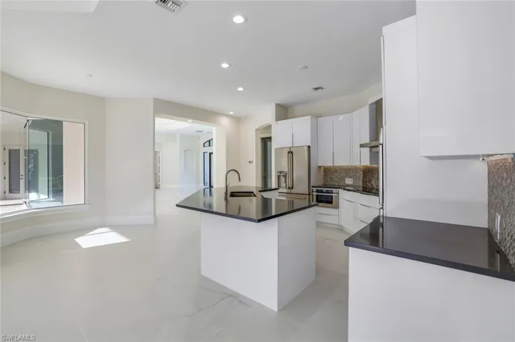 Kitchen with sink, white cabinetry, appliances with stainless steel finishes, an island with sink, and decorative backsplash