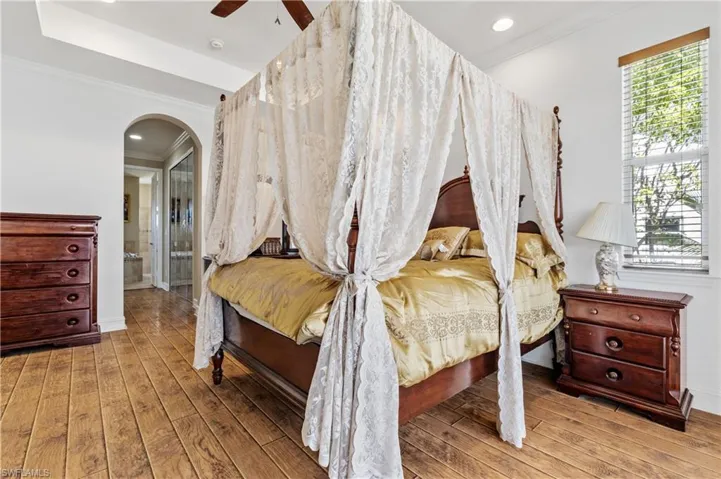 Bedroom featuring crown molding, arched walkways, ceiling fan, light wood finished floors, and recessed lighting