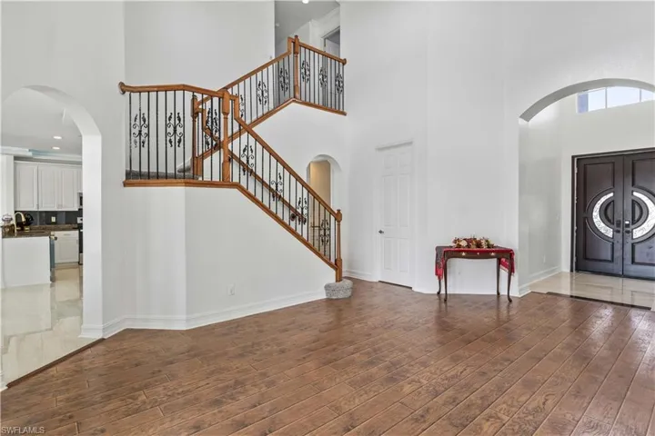 Entryway featuring a towering ceiling, hardwood / wood-style floors, stairs, and baseboards