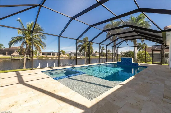 View of swimming pool featuring a sunroom, a pool with connected hot tub, glass enclosure, a patio, and a water view