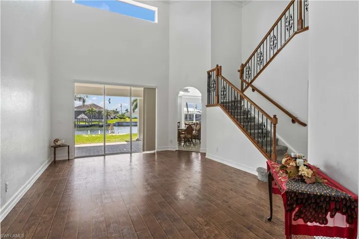 Foyer with arched walkways, a high ceiling, wood finished floors, and baseboards