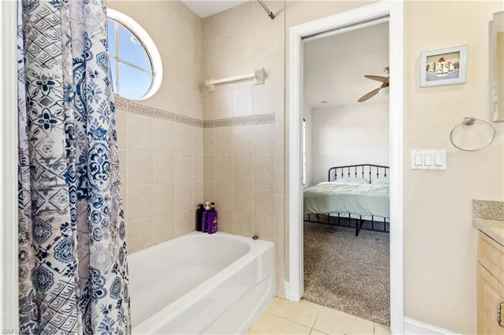 Full bathroom with vanity, light carpet, light tile patterned floors, connected bathroom, and shower / tub combo with curtain