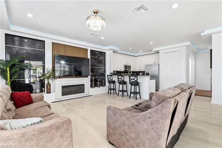 Living room featuring a glass covered fireplace, recessed lighting, arched walkways, and crown molding