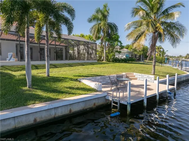 Dock with a patio, a yard, glass enclosure, a sunroom, and a water view