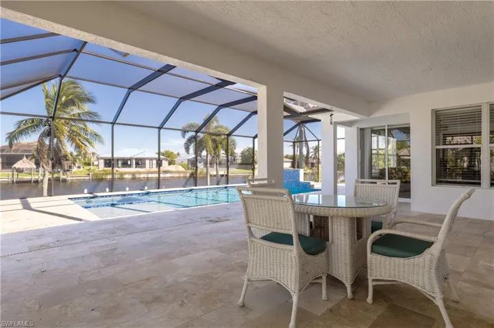 Swimming pool with a patio, a water view, a sunroom, glass enclosure, and outdoor dining space