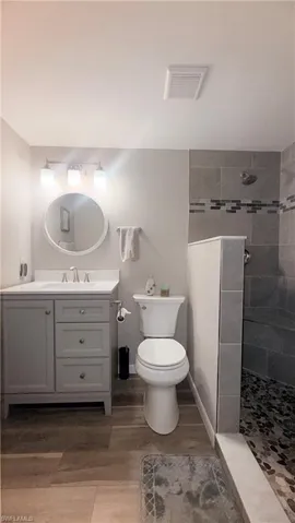 Full bath with a walk in shower, vanity, and light wood finished floors