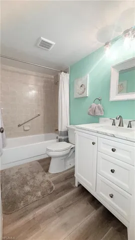 Full bathroom with vanity, shower / bath combo, and wood finished floors