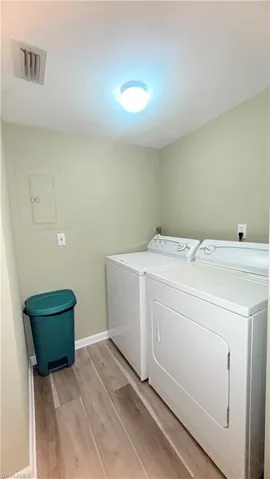 Laundry area featuring light wood-style flooring, washing machine and dryer, and electric panel
