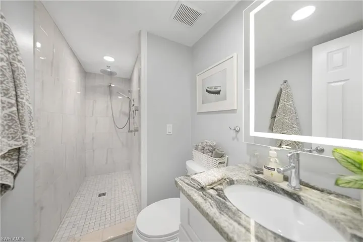 Bathroom featuring vanity, toilet, and tiled shower