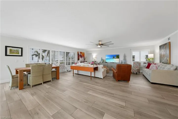Living room with ceiling fan, crown molding, and light wood-type flooring