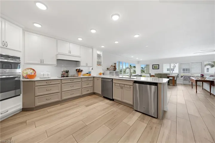 Kitchen featuring sink, backsplash, kitchen peninsula, white cabinets, and appliances with stainless steel finishes