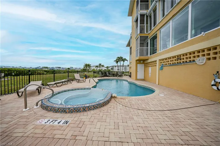 View of swimming pool with a patio and a hot tub