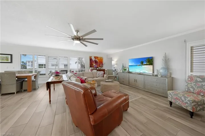 Living room with ceiling fan, light wood-type flooring, and ornamental molding