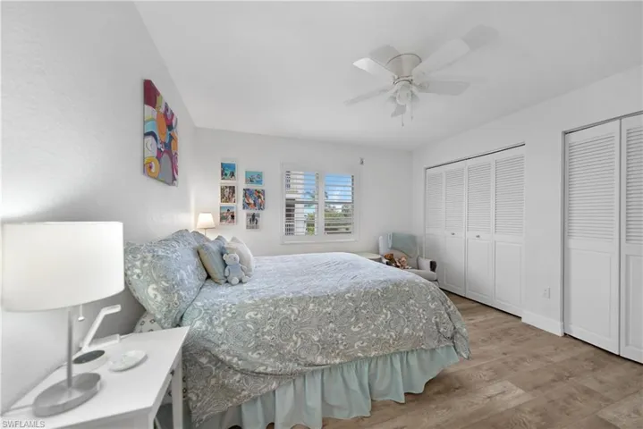 Bedroom with light wood-type flooring, ceiling fan, and multiple closets