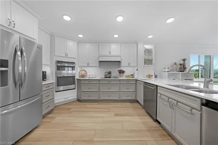 Kitchen with gray cabinetry, white cabinetry, sink, decorative backsplash, and appliances with stainless steel finishes