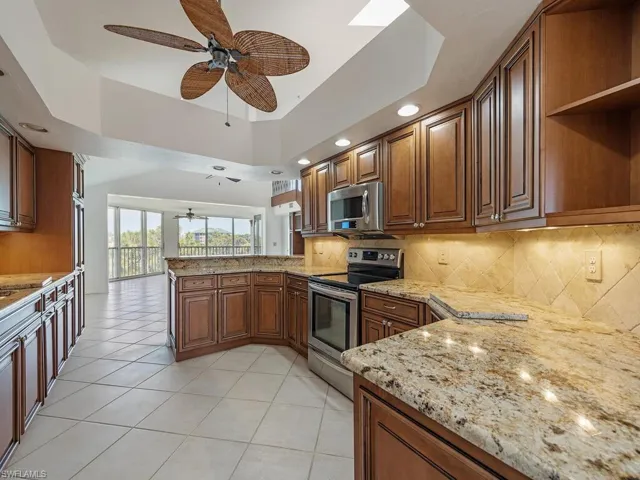 Kitchen featuring decorative backsplash, kitchen peninsula, ceiling fan, and stainless steel appliances