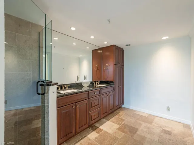 Bathroom with dual vanity, a shower with shower door, and tile patterned flooring