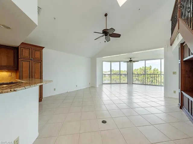 Unfurnished living room with high vaulted ceiling, light tile patterned floors, and ceiling fan