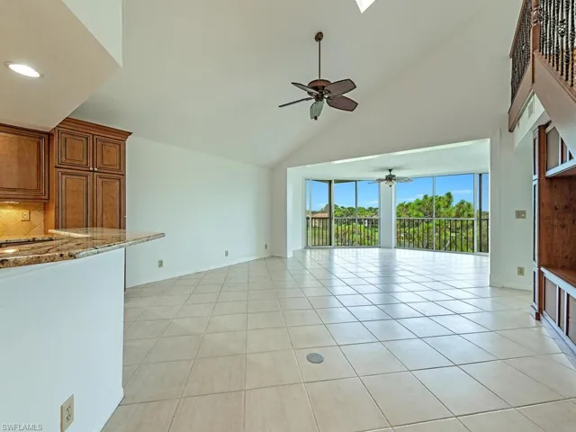 Unfurnished living room with high vaulted ceiling, ceiling fan, and light tile patterned floors