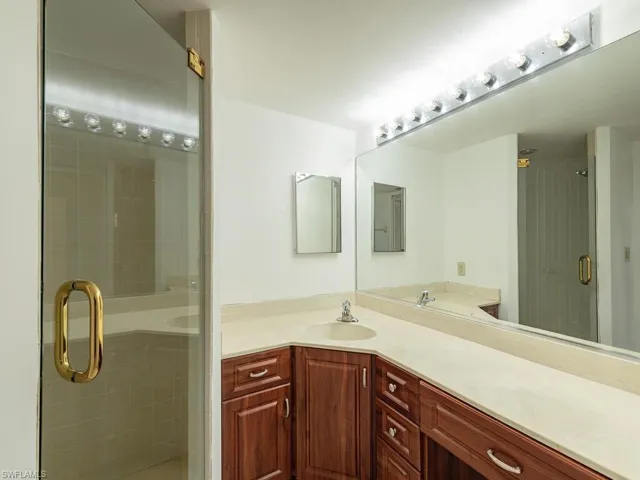 Bathroom featuring a shower with shower door and vanity
