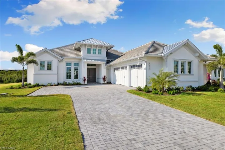 View of front of house featuring an attached garage, decorative driveway, a front yard, and stucco siding
