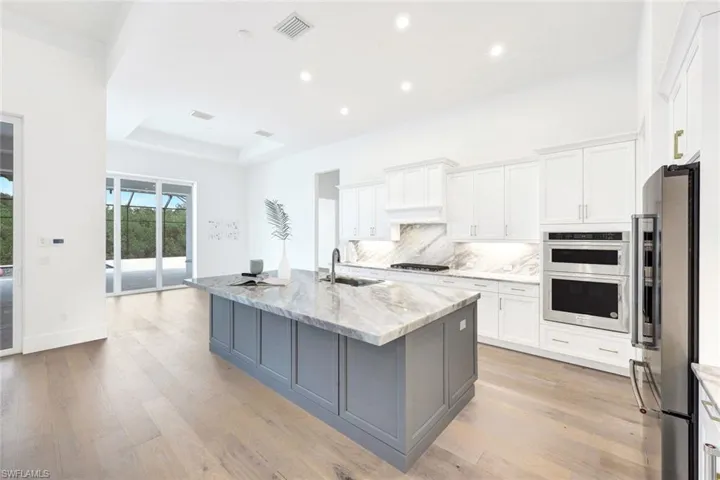 Kitchen featuring appliances with stainless steel finishes, decorative backsplash, light wood-style flooring, white cabinets, and recessed lighting