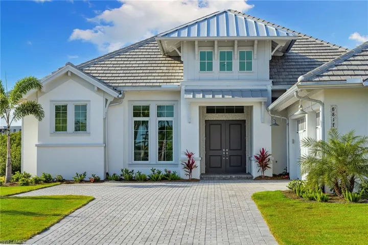 View of front facade with stucco siding, a high end roof, and a front yard