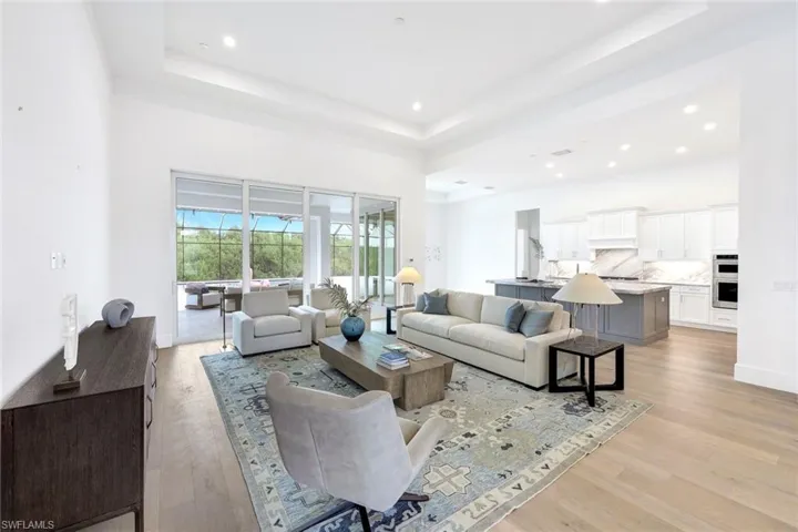 Living area with recessed lighting, light wood-style floors, and a tray ceiling