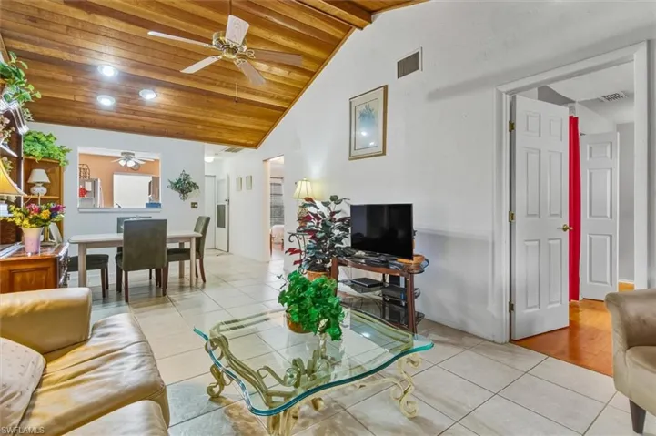 Living room with light tile patterned floors, wooden ceiling, recessed lighting, ceiling fan, and high vaulted ceiling